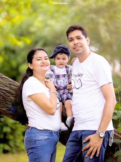 A happy family of three posing on a tree branch during their outdoor session. We use natural elements to add a unique touch to our family photography.