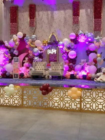 The purple lighting enhances the dreamy atmosphere of this baby shower decoration. The moon and star foil balloons add to the 'Twinkle Twinkle Little Star' vibe.