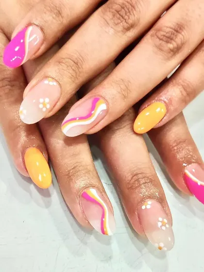 A vibrant summer manicure combining solid yellow and pink nails with abstract swirls and delicate daisy accents. This set has a little bit of everything.