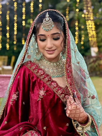 A close-up of the bride's serene expression. The soft shimmer on her eyelids and the dewy finish on her skin create an ethereal glow under the veil.