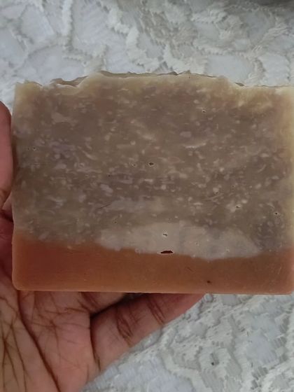 Holding a bar of the Pink Moon soap. It's crafted with coconut milk and rich butters for a creamy, moisturizing lather.