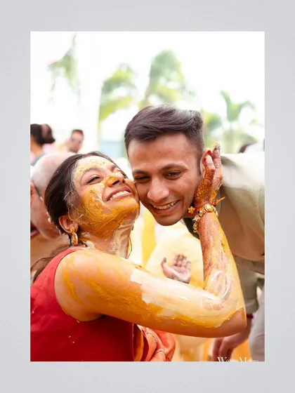 A candid moment of pure affection during the Haldi ceremony. The bride, covered in turmeric, pulls the groom in for a hug, showcasing the fun and love-filled atmosphere.