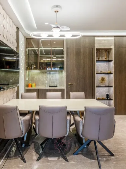 A side view of the dining space, showing its connection to the living area. The modern fan and chandelier, along with the recessed ceiling lights, create a layered and luxurious lighting scheme for any occasion.
