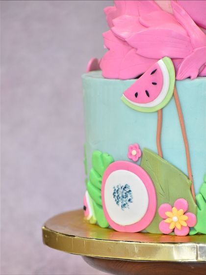 A detailed shot of the tropical flamingo cake, focusing on the handmade fondant watermelon slices, passion fruit, and tropical flowers that add to its vibrant, summery feel.