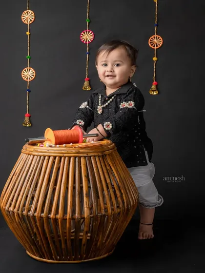 This little one is all smiles while playing with a spool of kite string. The dark background makes his happy face and the festive decorations stand out.
