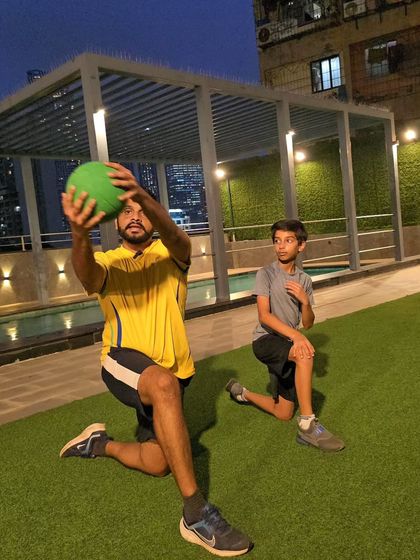 Here, a coach and athlete work on a kneeling medicine ball exercise. This drill isolates the core and upper body, building the rotational strength needed for hitting sixes and bowling with pace.