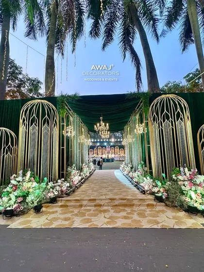 The grand entrance to the event, with towering gold structures, lush florals, and a welcome sign.