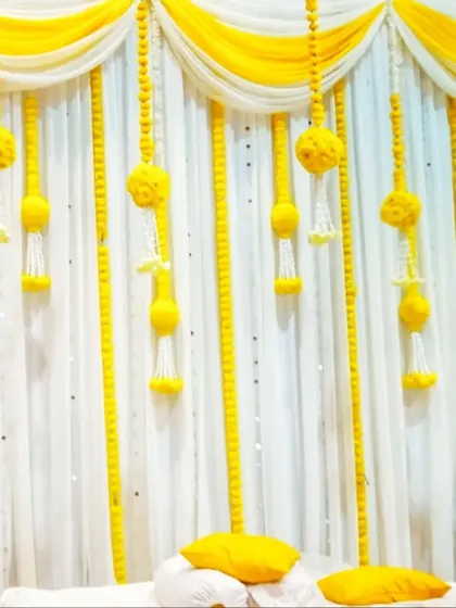 A simple and elegant backdrop I designed for a Haldi ceremony. The setup uses a clean white curtain with hanging marigold and tuberose garlands, creating a traditional and bright setting for the pre-wedding ritual.