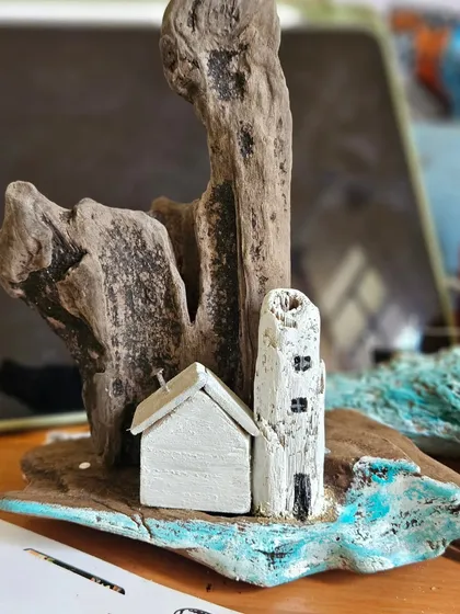 This is what my workbench looks like when a new driftwood collection is taking shape. Here, the blank canvases of the lighthouse and house are waiting for their details, sitting beside the raw, organic shape of the wood that will become their landscape.
