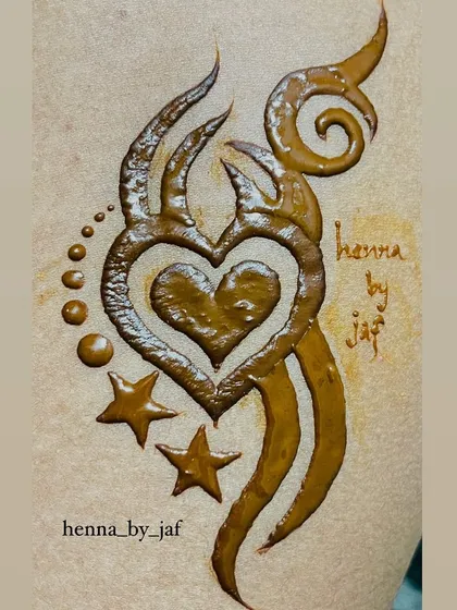 A bold, tribal-style henna tattoo featuring a heart at its center, surrounded by stars and swirls.