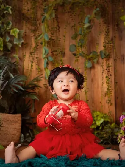 A happy little girl playing in her own enchanted garden. The vibrant red dress contrasts beautifully with the lush greenery.