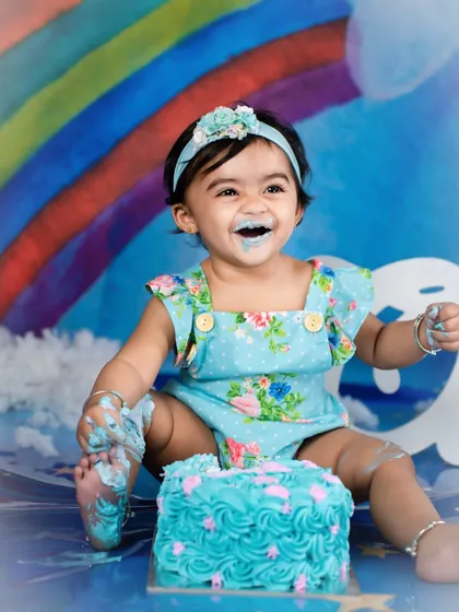 The pure joy of a messy cake smash. This little girl's laughter is infectious as she enjoys her rainbow-themed birthday celebration.
