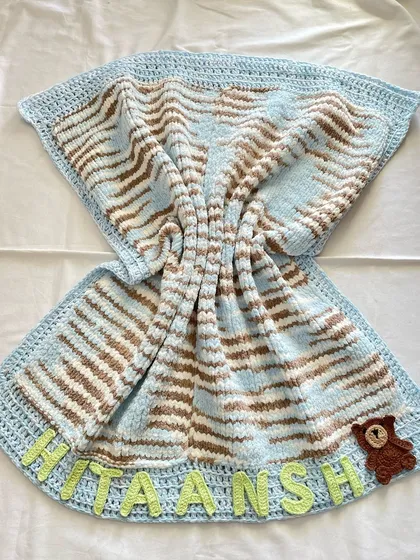 This is our premium "Cuddle Blanket," and it's as soft as it looks. Unlike our other blankets, this one is knitted to create an extra plush and heavy feel. We personalized this one with the baby's name, "Hitaansh," and a small teddy bear appliqué, making it a truly unique newborn gift.