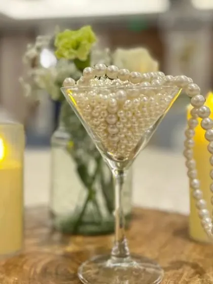 It's all in the details. This elegant centerpiece features pearls in a martini glass and flameless candles on a rustic wood slice, adding a touch of class and sophistication to the table decor.