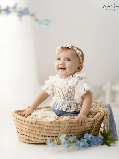 A full-length portrait of the baby girl in a basket, looking up with a happy and hopeful expression.
