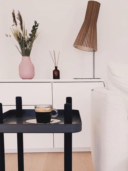 The classic Secto 4210 table lamp adds a touch of Scandinavian elegance to a modern living room sideboard.