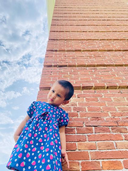 A low-angle shot of my daughter in her strawberry dress, looking up at the sky. It captures her curious and playful spirit.