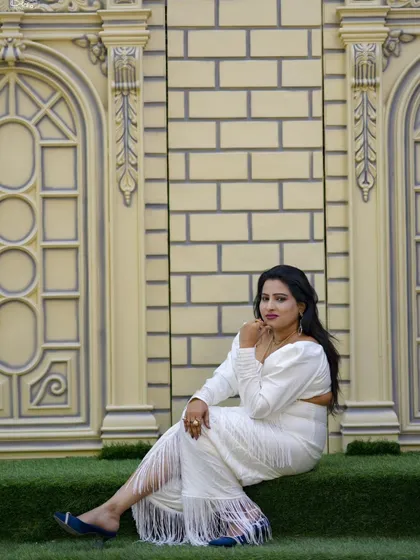 A full-length portrait showing off a modern fringed saree. The elegant backdrop adds a touch of class to this personal photoshoot.