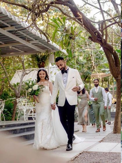 A grand entrance of the bride and groom with their wedding party. The tree-lined path at Farmhouse Collective serves as a natural aisle for this beautiful procession.