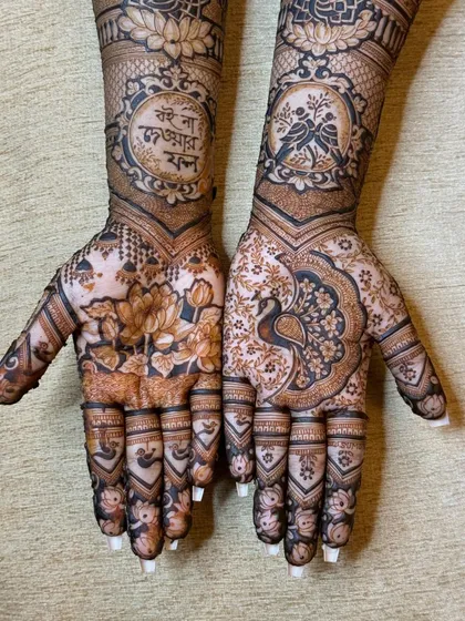 A stunning pair of hands featuring a mix of floral, peacock, and personalized motifs, showing how two different designs can be beautifully coordinated.