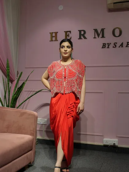 A full-length view of me wearing the red draped skirt with the embellished jacket.