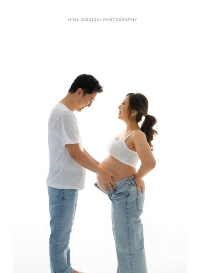 A full-length view of a happy couple in our bright, minimalist studio. This is a classic example of a simple and timeless pregnancy photoshoot.