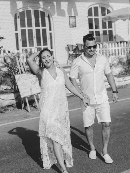 A joyful, candid black and white photo of the couple walking down a street in Goa. Her laugh is infectious, and the shot feels full of life and happiness.