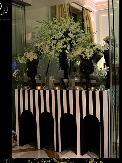 A console table with a modern black and white striped design, topped with large arrangements of white flowers.