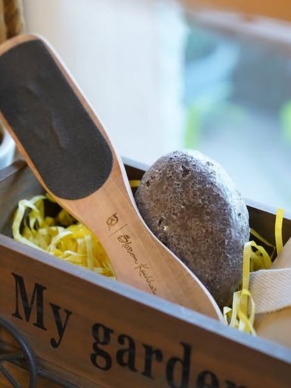 A charming "My Garden" cart holding our foot care accessories, including a pumice stone and a wooden foot file, perfect for a luxurious pedicure at home.