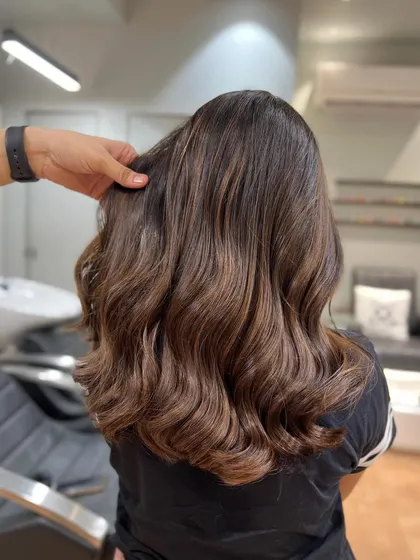 A classic brunette brown balayage. The highlights are subtly woven through the hair to create a natural, sun-kissed effect.