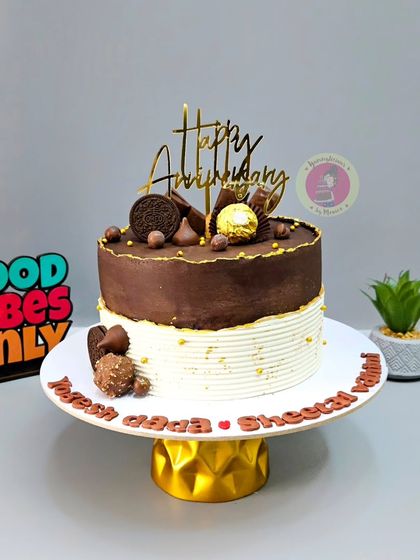 A half-and-half anniversary cake, combining a rich chocolate top with an elegant white base, decorated with Ferrero Rocher and Oreos.
