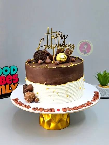 A half-and-half anniversary cake, combining a rich chocolate top with an elegant white base, decorated with Ferrero Rocher and Oreos.
