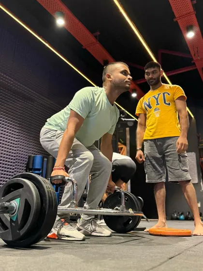 Proper coaching makes all the difference in heavy lifts. I am closely supervising this client's form during a heavy trap bar deadlift to ensure his back remains straight and the lift is performed safely and effectively.