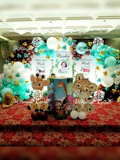 The main stage for the twin baby welcome and birthday party, featuring a dense arch of green, white, and brown balloons and adorable animal characters.
