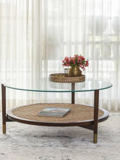 The Bagh Centre Table combines the richness of wood and rattan with the lightness of glass. The lower rattan shelf provides a space for display, while the brass-tipped legs add a touch of modern sophistication.