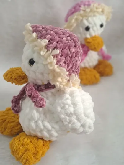 A sweet white duck plushie wearing a cozy winter hat and scarf.