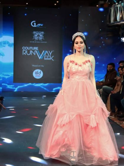 The full look on the Couture Runway Week stage. The pink ball gown makes a statement with its voluminous skirt and detailed bodice, creating a fairytale moment.