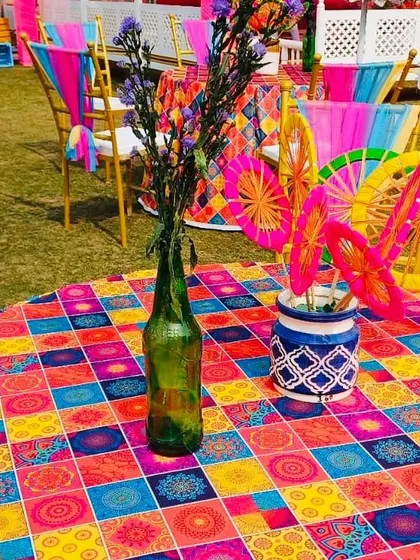 Even the table decor matches the theme. This photo shows a colorful tablecloth and quirky centerpieces for a Haldi carnival event.