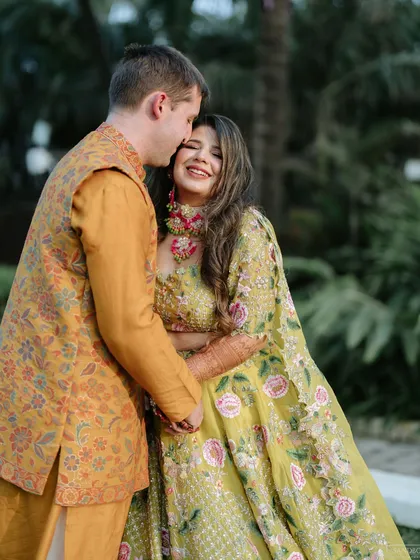 A sweet, affectionate moment between the couple at their Haldi, with the groom kissing the bride's forehead.