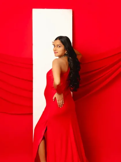 A striking pose in our bold red one-shoulder gown, showcasing its sleek silhouette and thigh-high slit.