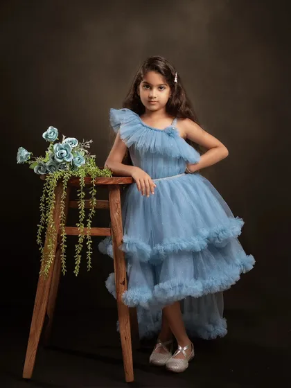 A classic and elegant portrait for a seventh birthday. The beautiful blue dress and simple floral prop create a timeless look. This style of photography is perfect for creating a formal portrait that can be treasured for years to come.
