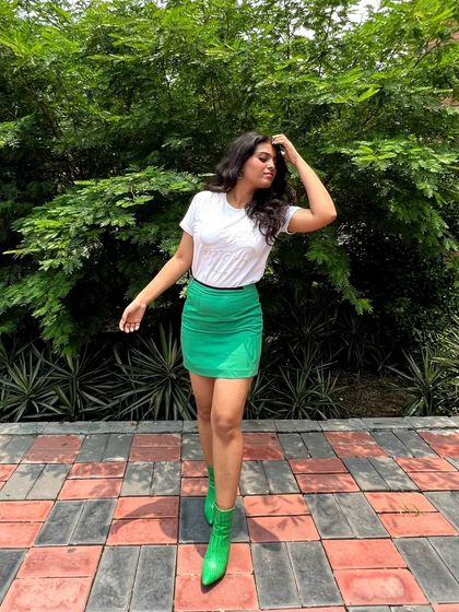 A simple but bold outfit formula: a basic white tee, a vibrant green mini skirt, and matching green ankle boots. This monochrome pop of color is an easy way to elevate a casual look.