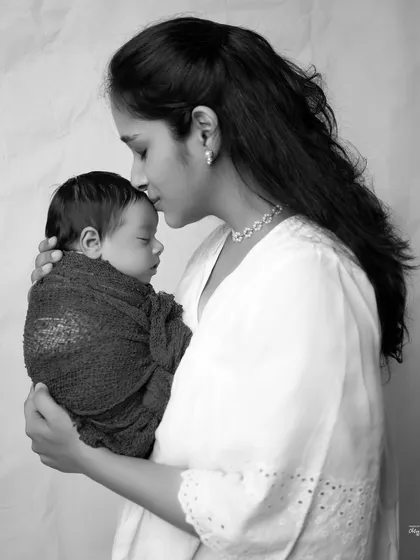 A mother's gentle kiss on her baby's head, captured in a beautiful monochrome profile. It's a simple, powerful image of maternal love.
