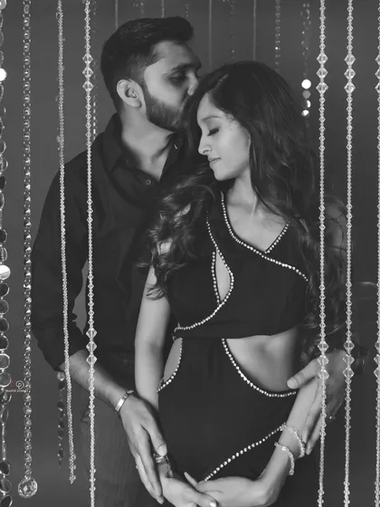 A close-up in black and white, highlighting the gentle kiss and the protective hands around the baby bump. A truly romantic and heartfelt image.