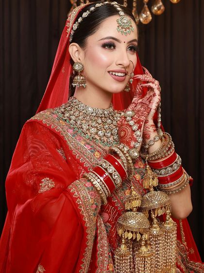 A beautiful bride in her red lehenga, with her hands adorned with intricate mehandi, showcasing the complete bridal look.