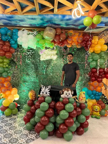 Proudly standing by the finished jungle-themed birthday decoration.
