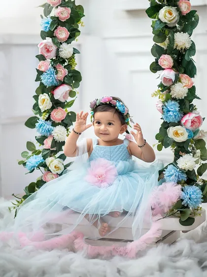 Waving hello from her floral wonderland. This swing, decorated with beautiful pastel flowers, is one of our most popular props for sitter sessions.