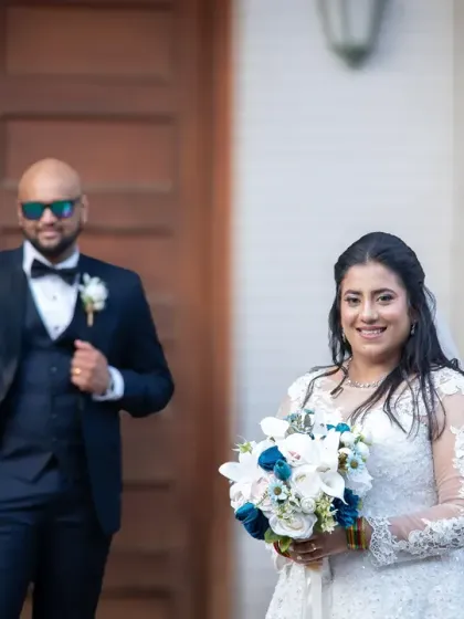 A lovely candid-style portrait of the bride and groom. The focus is on the bride's happy expression as she holds her bouquet, with her new husband looking on.