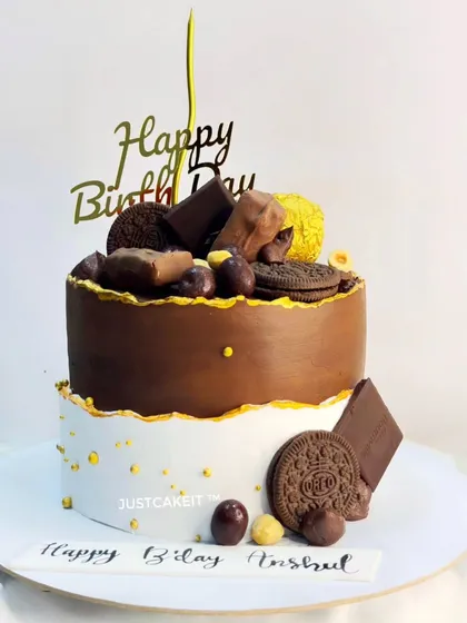 An intense dark couverture chocolate cake made as a surprise for a husband's birthday. The combination of rich chocolate, gold accents, and assorted toppings makes it a sophisticated and decadent choice.