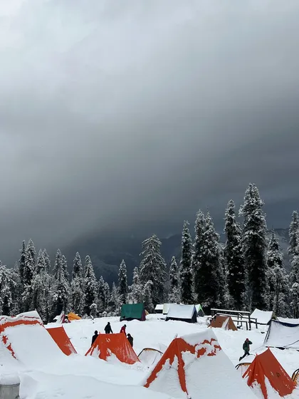 Our campsite at Kedarkantha under a dramatic, cloudy sky. Even without the sun, the beauty of the snow-covered landscape is undeniable.